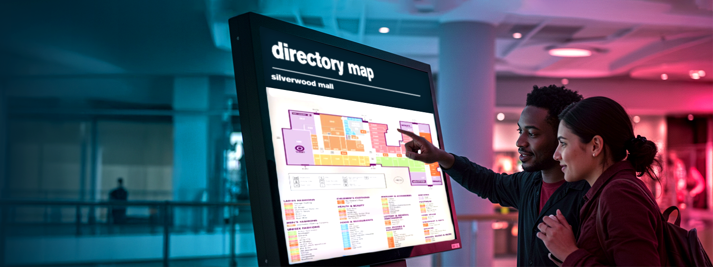 a man and woman viewing a directory map in a mall