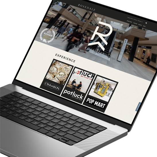 Laptop showing a shopping center website's Experience page featuring dining and retail tenants