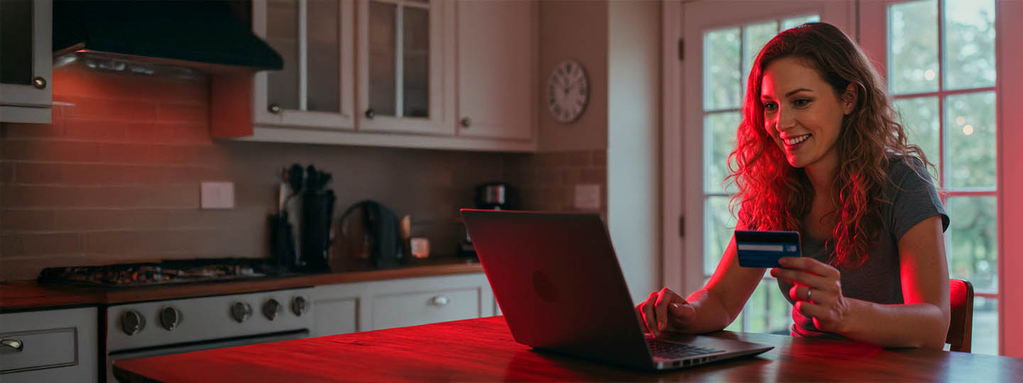Girl holding card and working on laptop