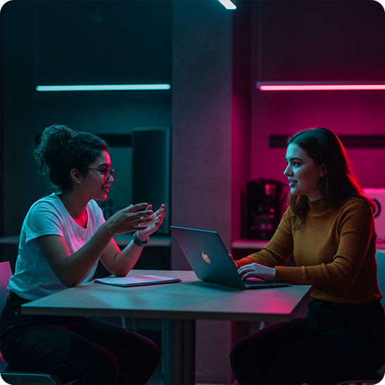 Two colleagues discussing social media strategy across a table with a laptop